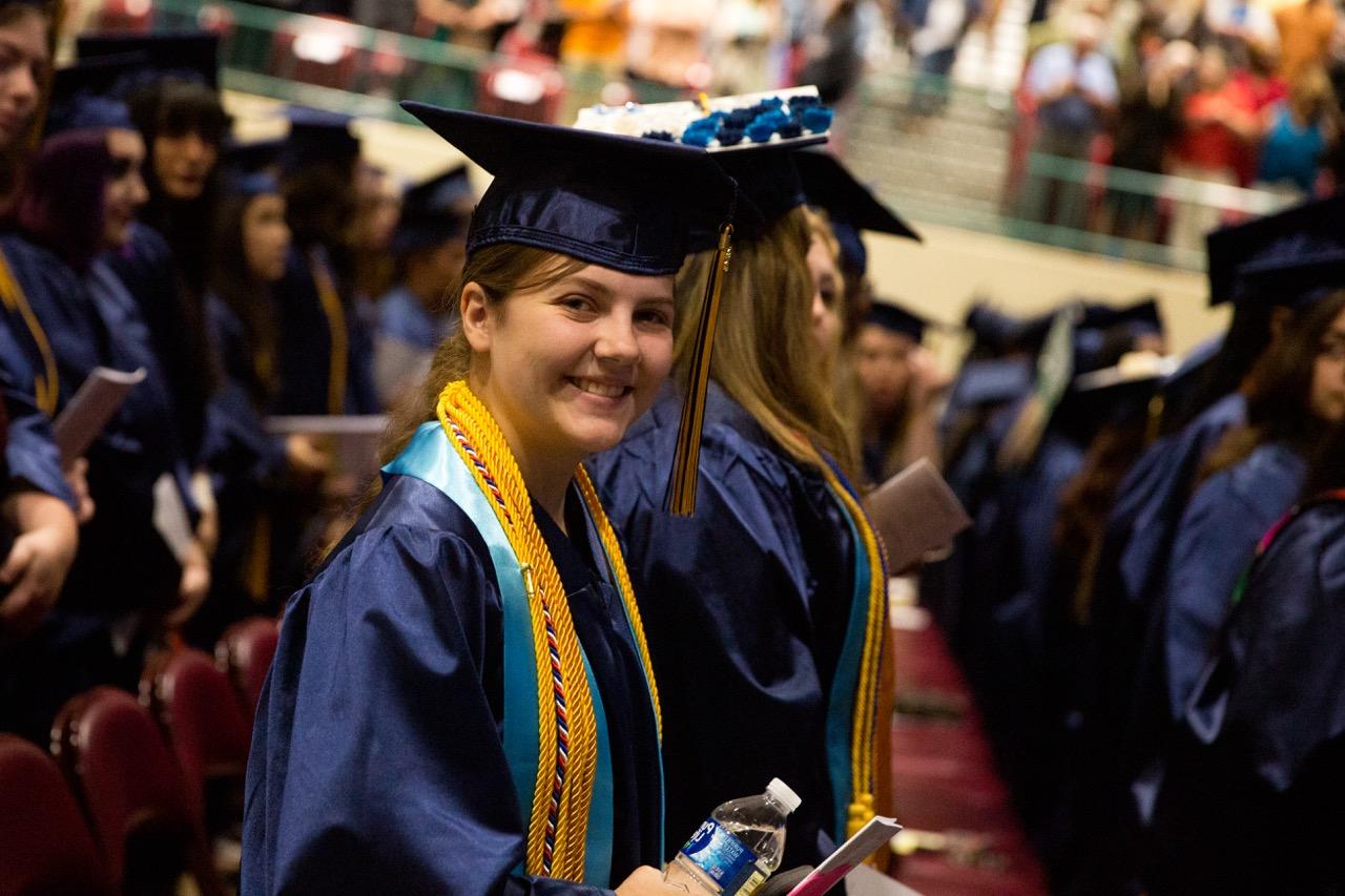 <br />
一位身着毕业礼服的女学生在毕业典礼上对着镜头微笑.