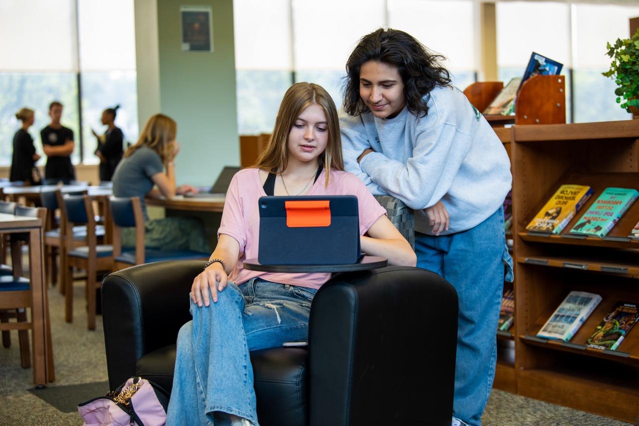 两个学生在图书馆，用iPad学习和研究.